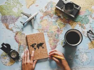 libro di viaggio, macchina fotografica, caffè, occhiali, bussola, aereo giocattolo, cartina