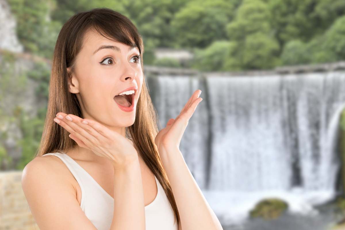 Ragazza meravigliata e cascata da sfondo