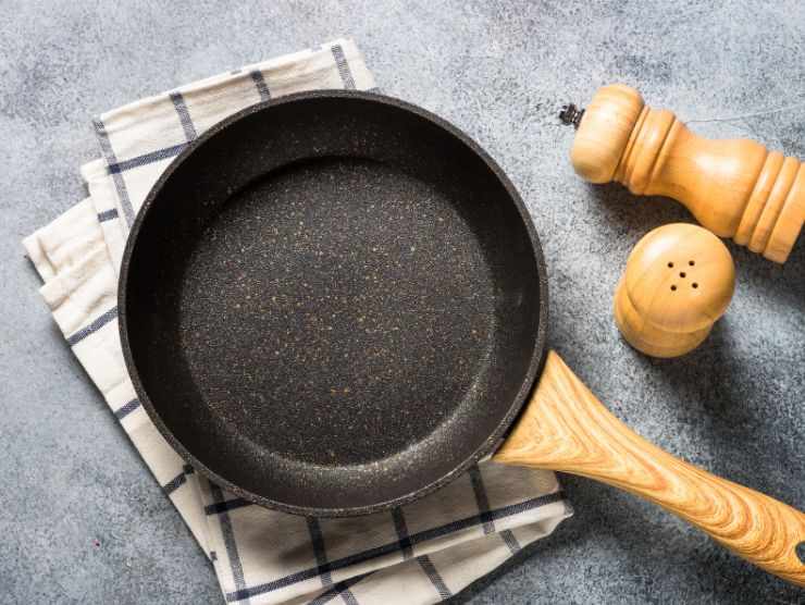 padella antiaderente su panno da cucina con saliera e pepiera accanto