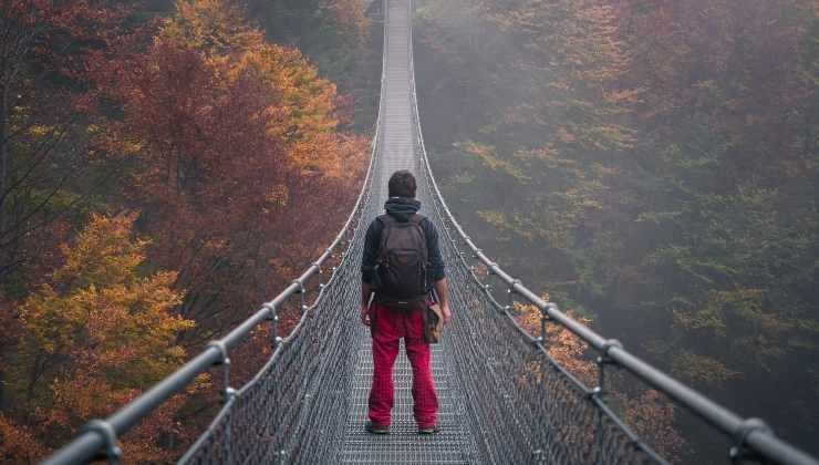 ragazzo attraversa ponte tibetano